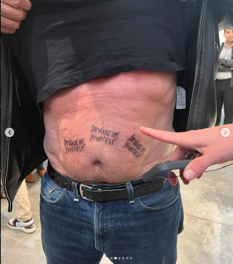 A man's stomach stamped with the words "beware of yourself"